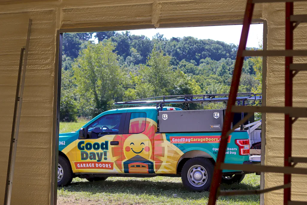 Good Day Garage Doors branded service pickup viewed through a spray-foam insulated garage door opening.